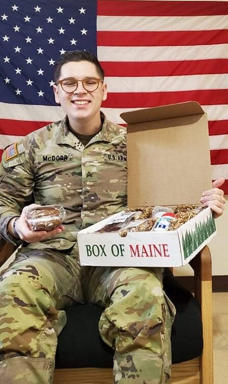 A U.S. Army soldier holding treats from his Box of Maine care package
